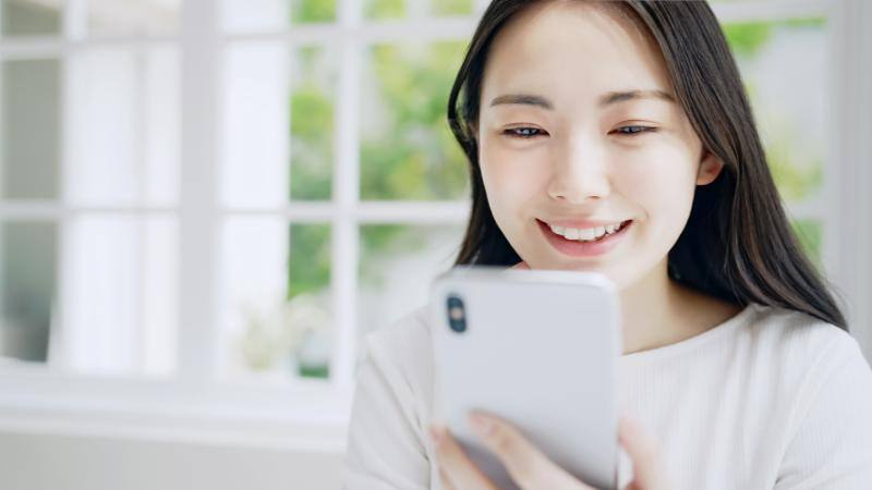 笑顔でスマートフォン画面を見る女性