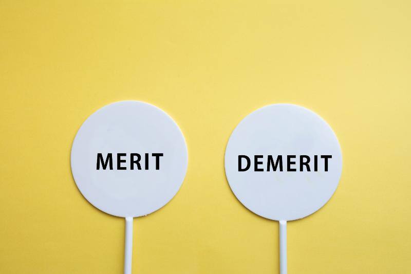 黄色背景に並ぶ「MERIT」と「DEMERIT」の文字が書かれた２つの丸い札