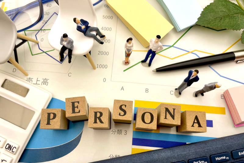 ブロックを並べて作った「PERSONA」の文字やグラフ、計算機や付箋などに囲まれて考えるミニチュアの人々