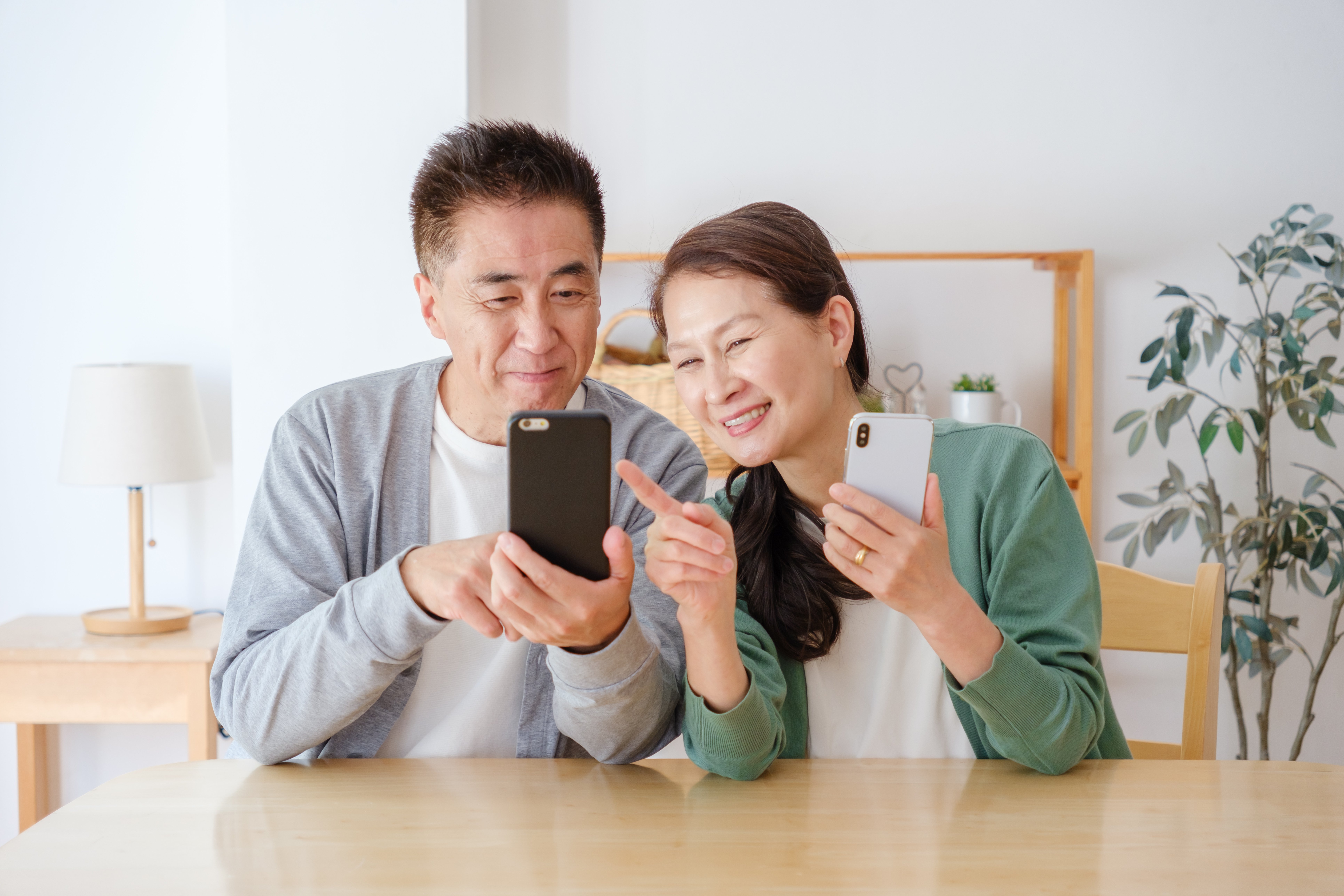 お互いのスマートフォンを片手に操作を確認するシニア男女