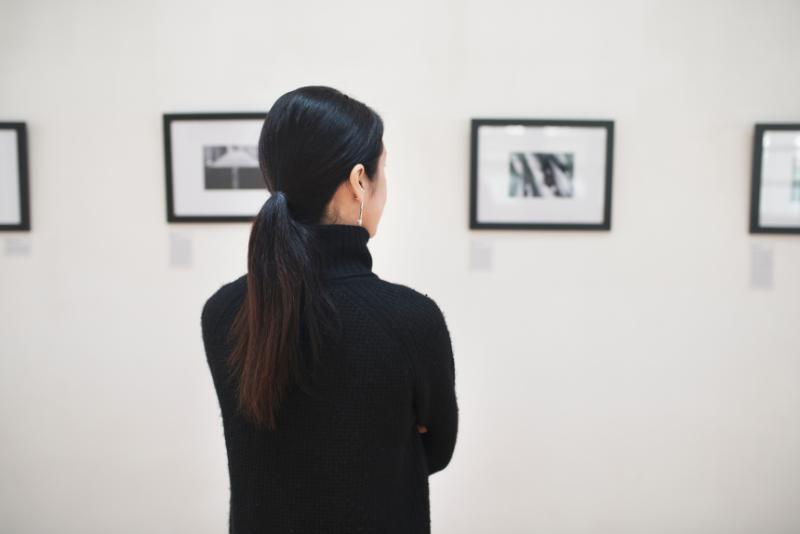 壁に展示された作品群を見つめる後ろ姿の女性