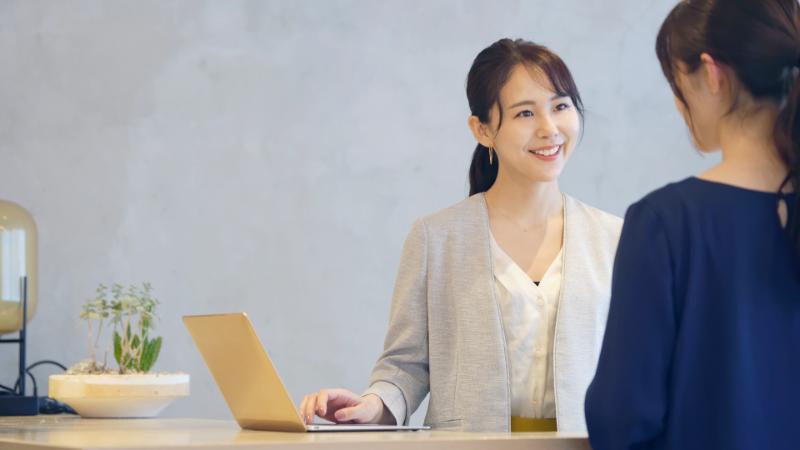 PCを片手に女性と話す女性