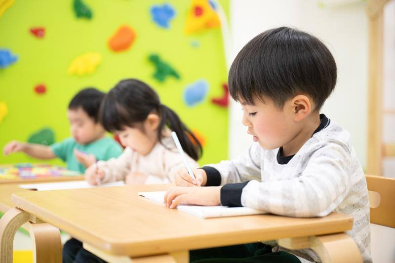 机上でノートにメモをする３人の子供