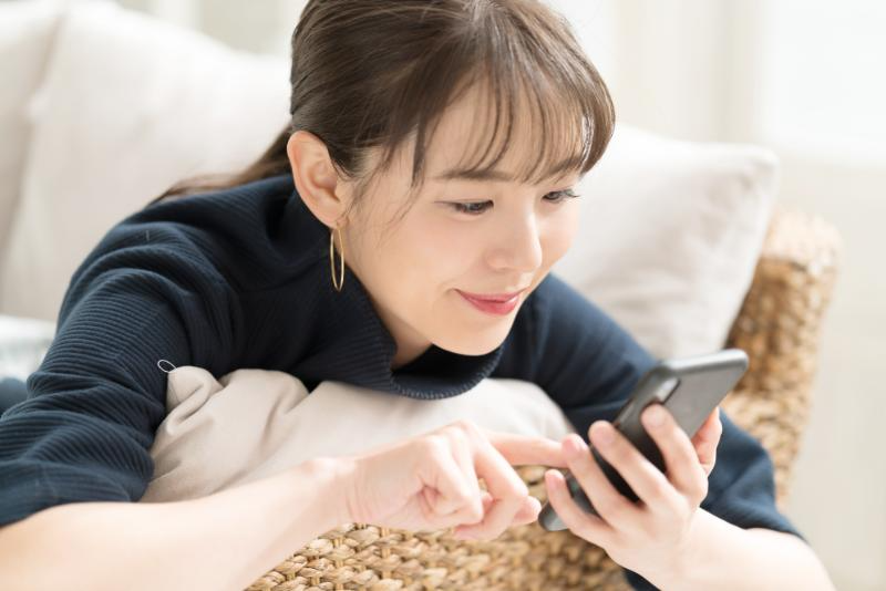 ソファーでスマートフォンを操作する女性