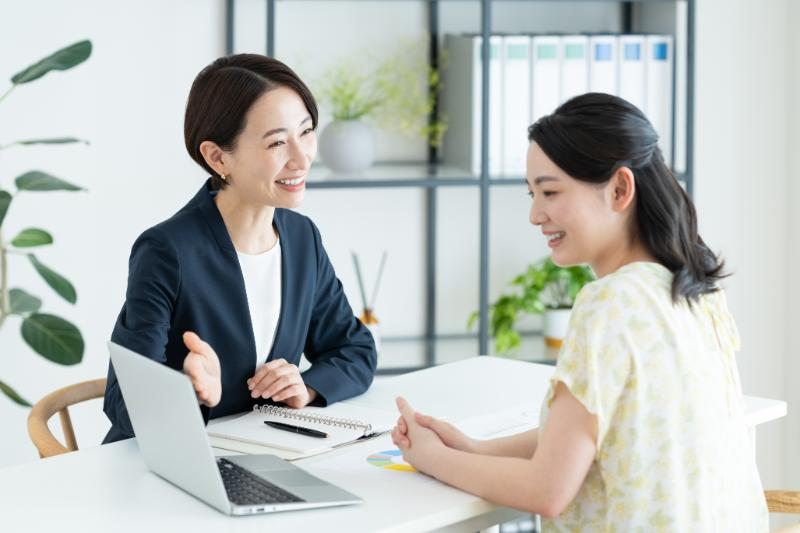 女性顧客にPCを用いて説明する笑顔の女性